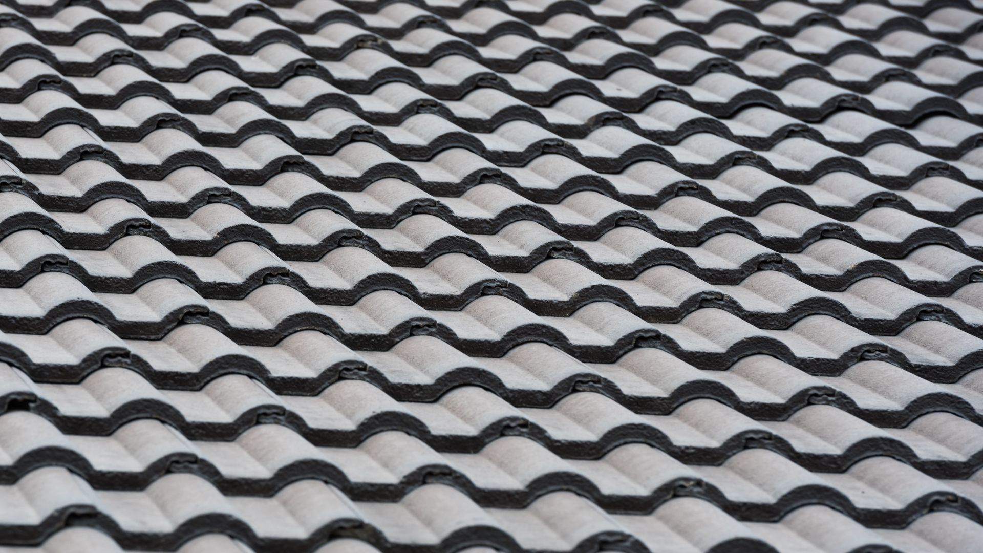 Gray wave-patterned roof tiles arranged in rows, viewed from above.