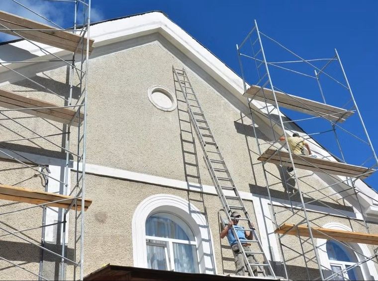 Scaffolding and a ladder on the exterior of a stucco building under construction.