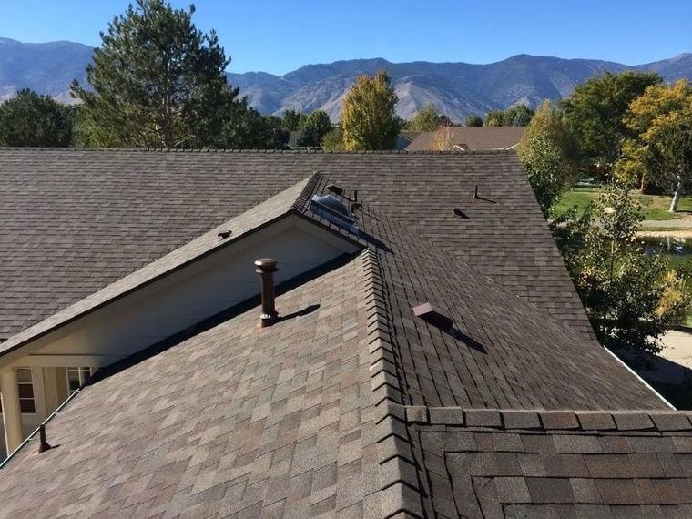 Roof with workers inspecting shingles, mountains and trees in the background