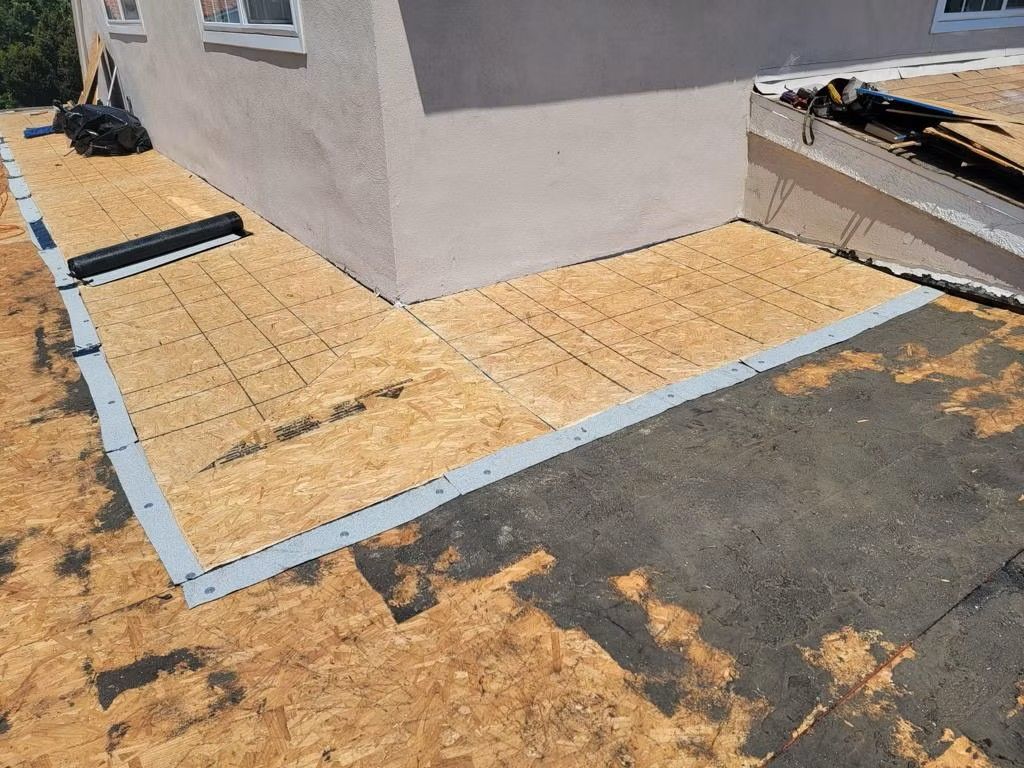 New wood subfloor and gray trim beside a house under construction, next to torn-up ground
