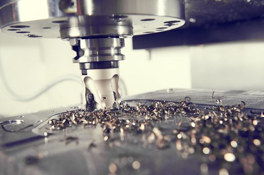 A machine is cutting a piece of metal on a table.
