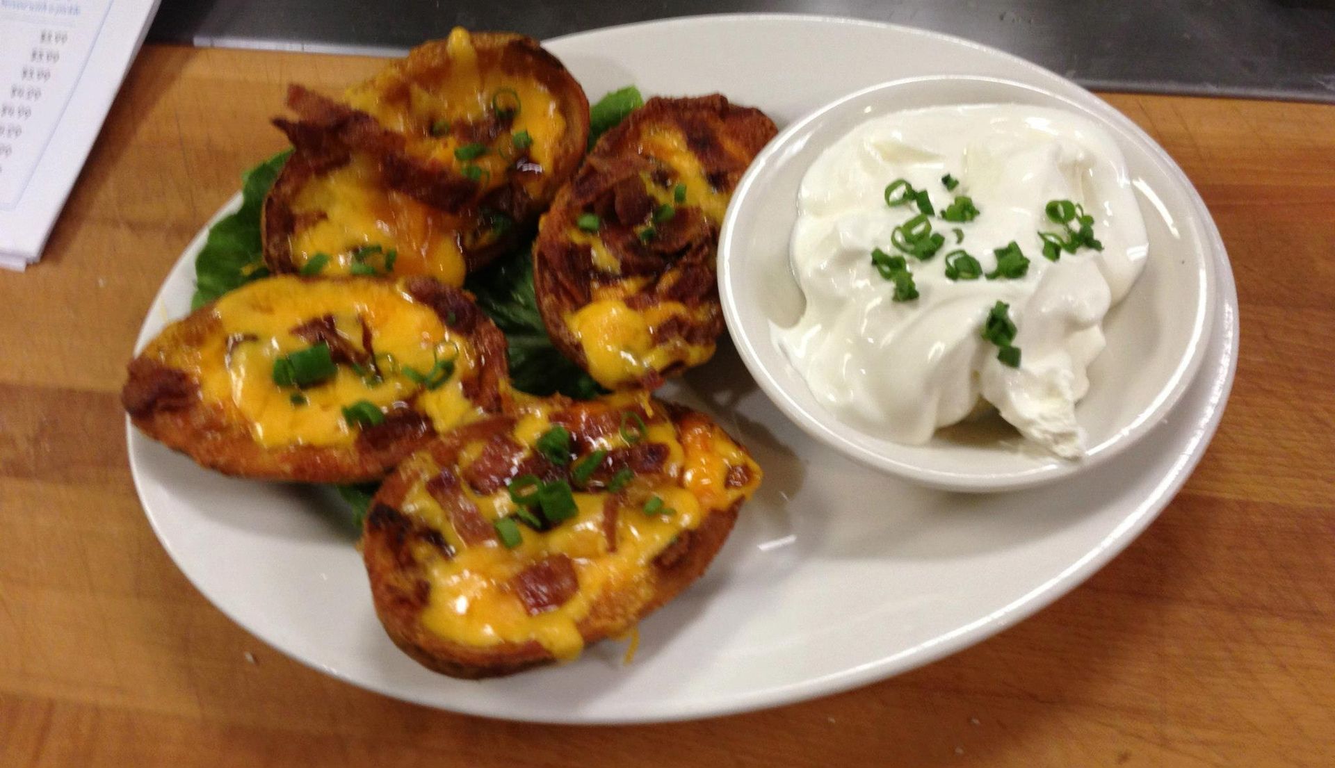 A plate of food with a bowl of sour cream on a table.