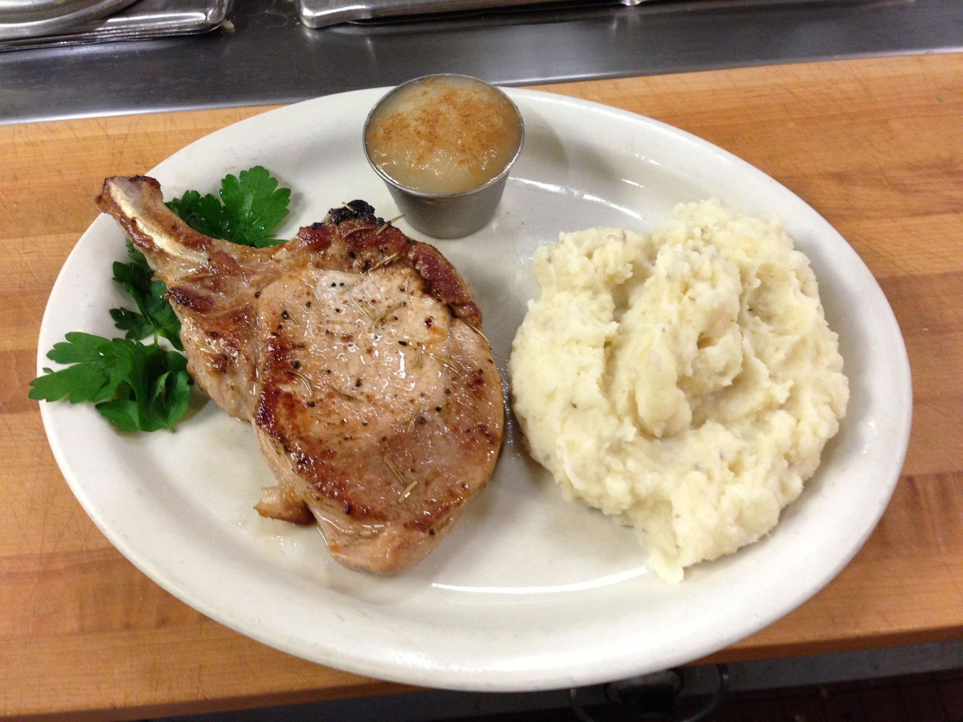 A white plate topped with meat and mashed potatoes on a wooden table.