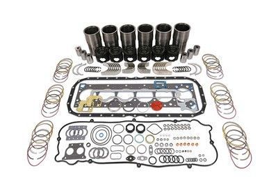 Piezas del kit de reconstrucción del motor dispuestas sobre una superficie blanca, incluidas juntas, pistones y sellos.