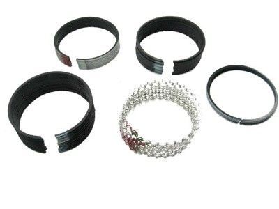 Cinco anillos de pistón, incluido un anillo de aceite de varias piezas, exhibidos sobre un fondo blanco.