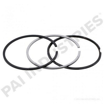 Tres anillos de pistón de motor: negro, plateado y un anillo negro con superficie texturizada, superpuestos.
