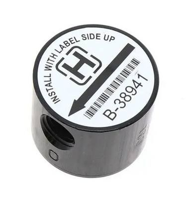 Pieza cilíndrica negra con etiqueta blanca marcada "INSTALAR CON EL LADO DE LA ETIQUETA HACIA ARRIBA", código de barras y "B-38941".