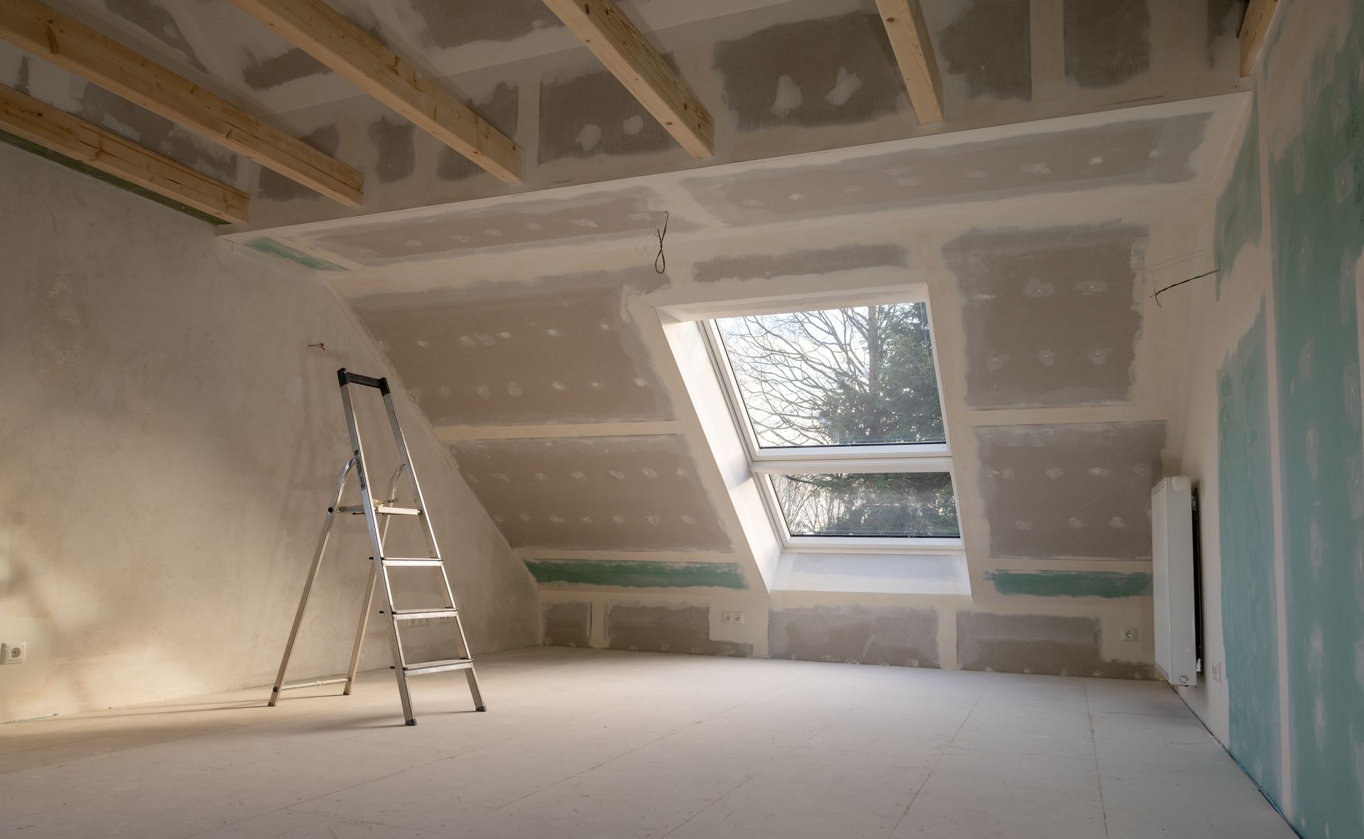 Man installing tile in bathroom, using a drill. Walls are partially tiled.