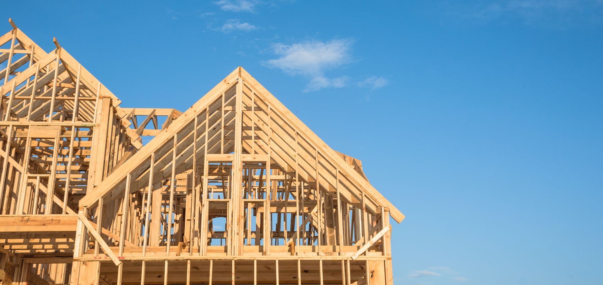 Wooden framework of a house against a blue sky.