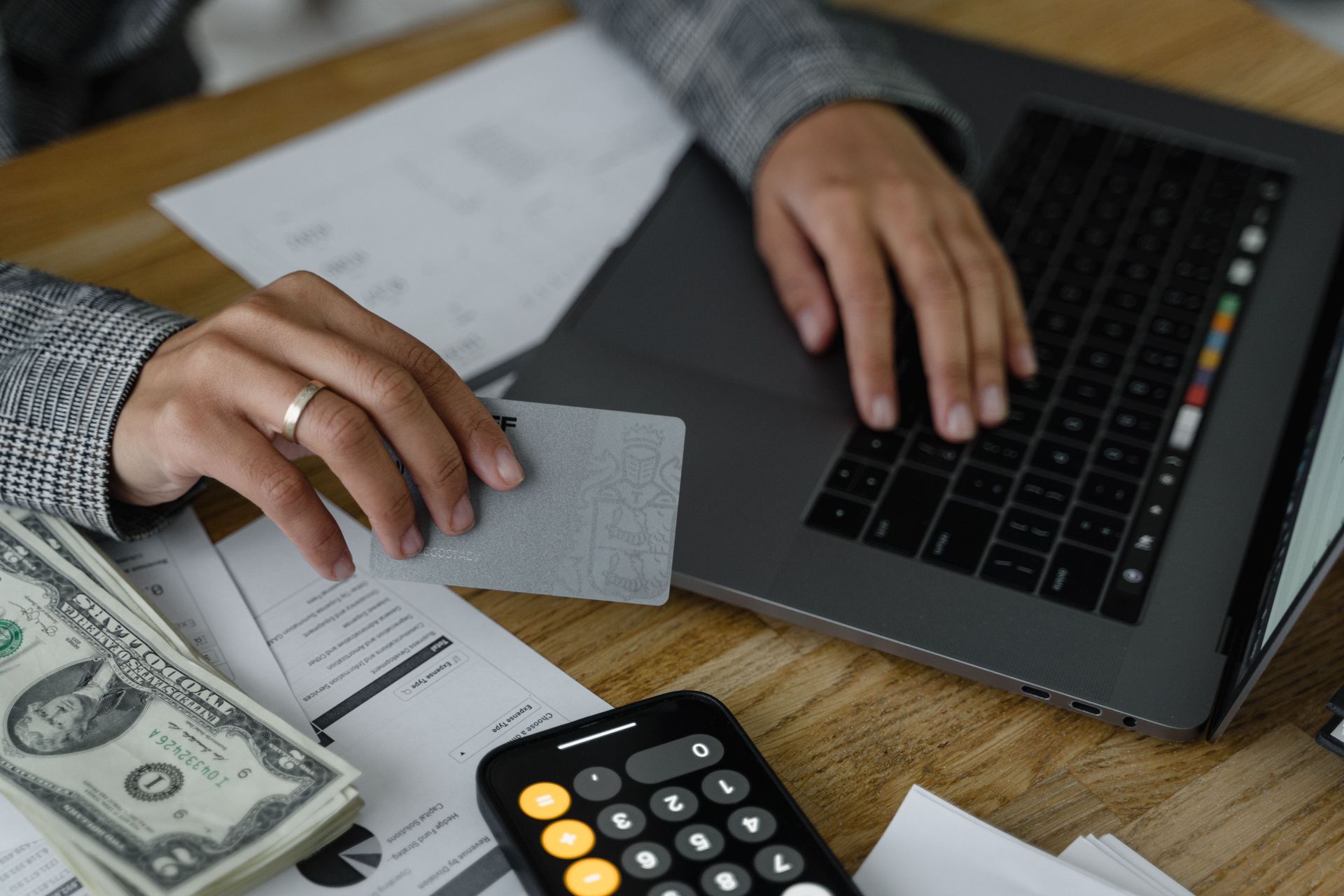 A business owner comparing a printed profit and loss statement to their bank account balance on a ph