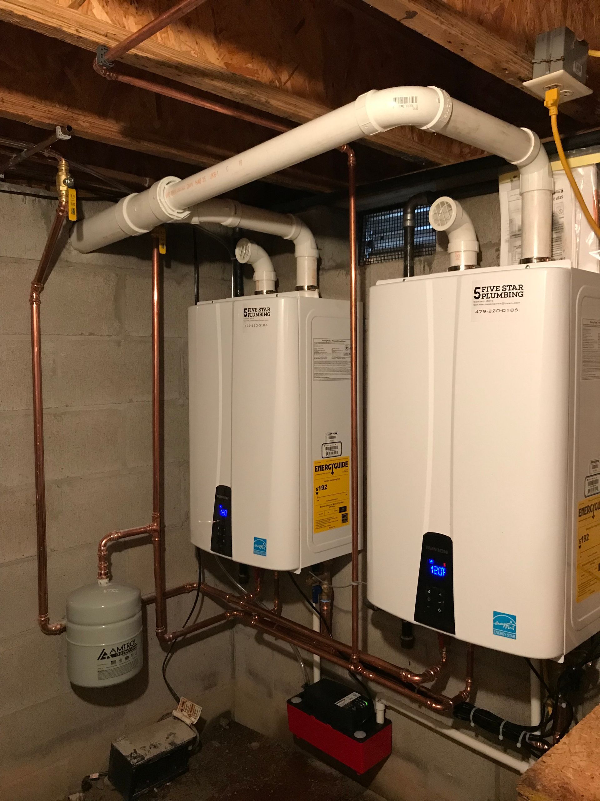 Three water heaters are connected to copper pipes in a basement.