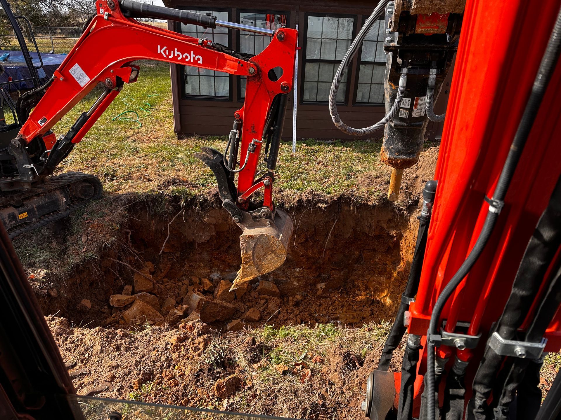 A red kubota excavator is digging a hole in the ground
