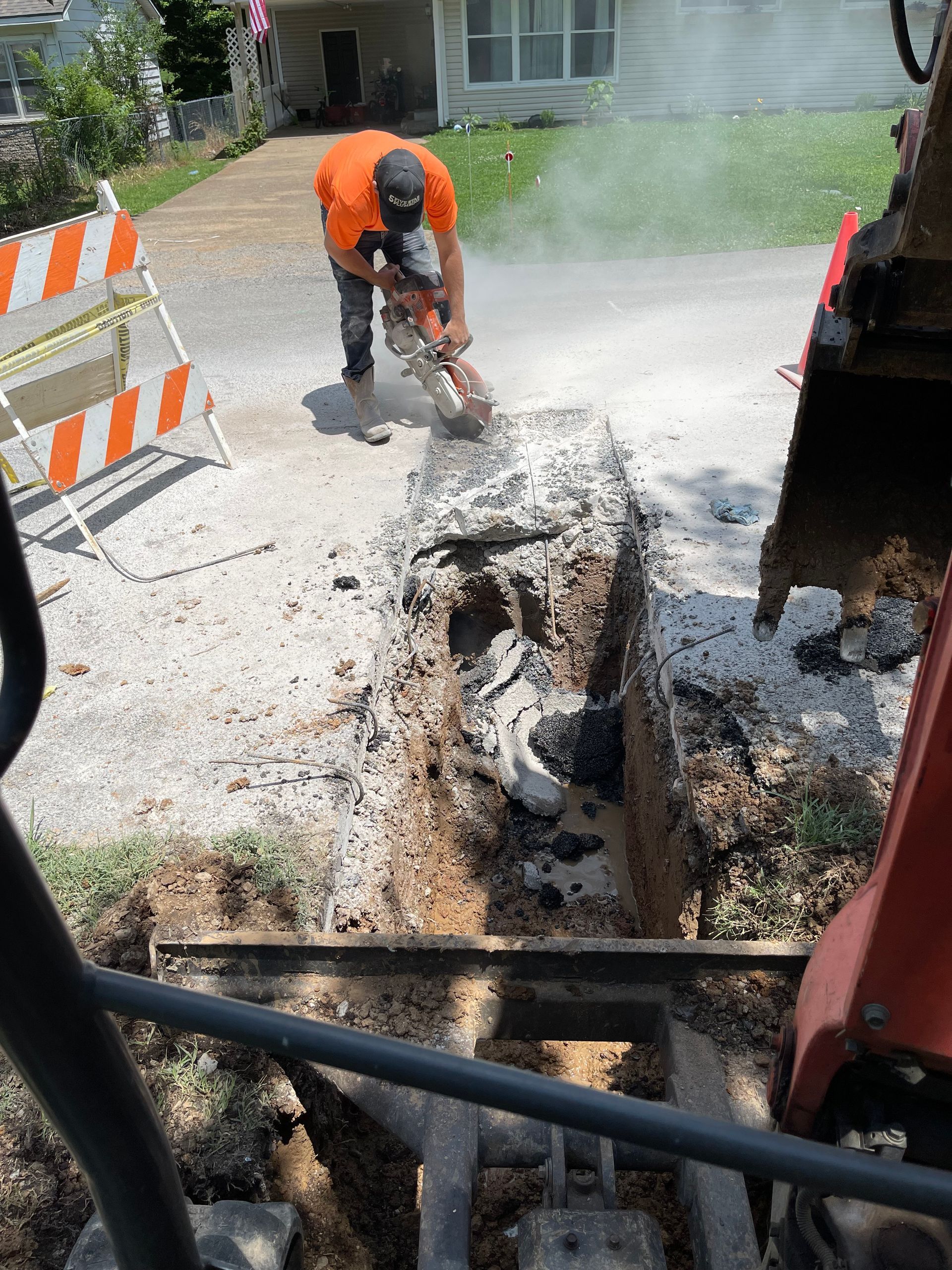A man is using a chainsaw to cut a hole in the ground