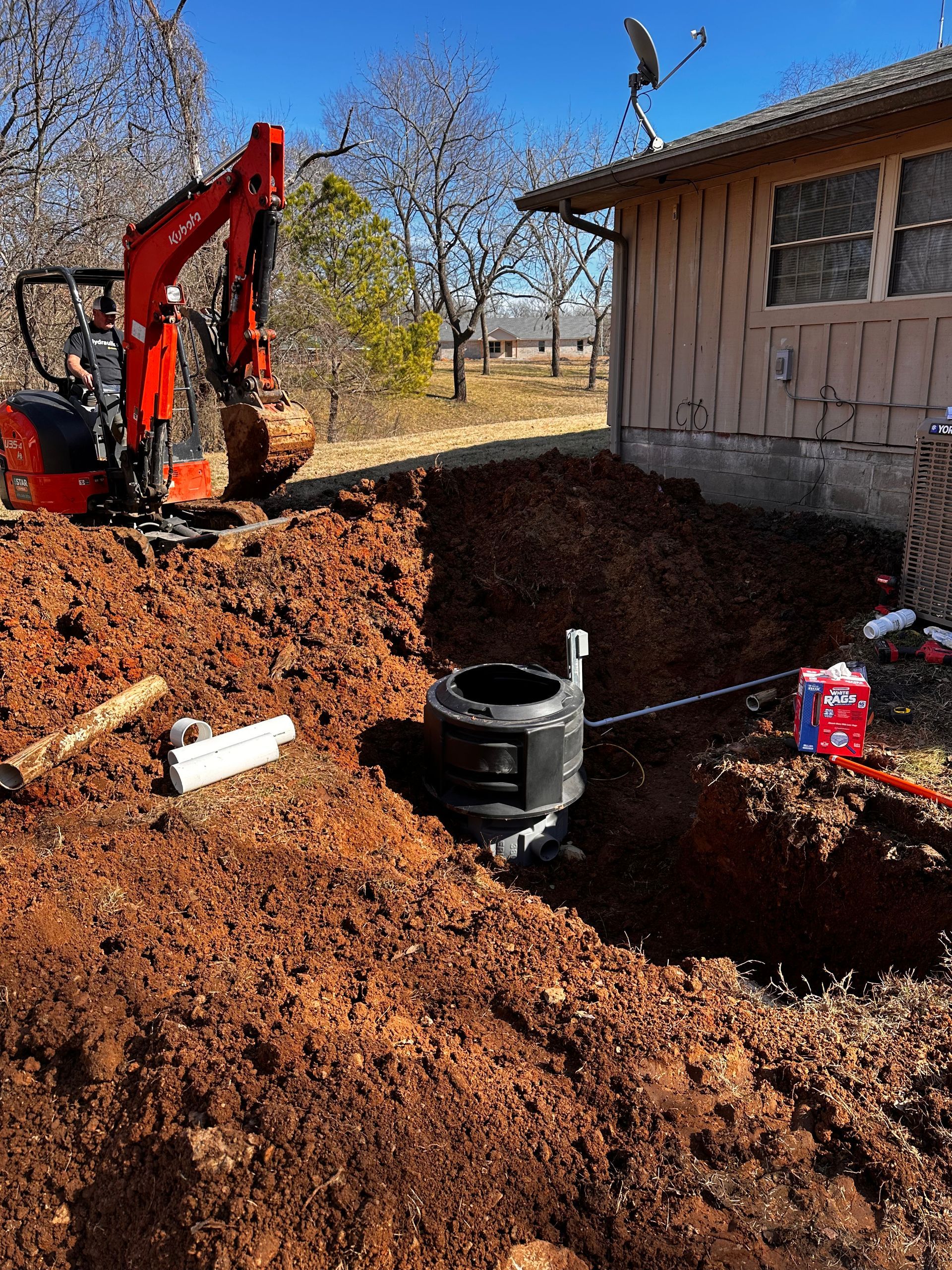 An excavator is digging a hole in front of a house