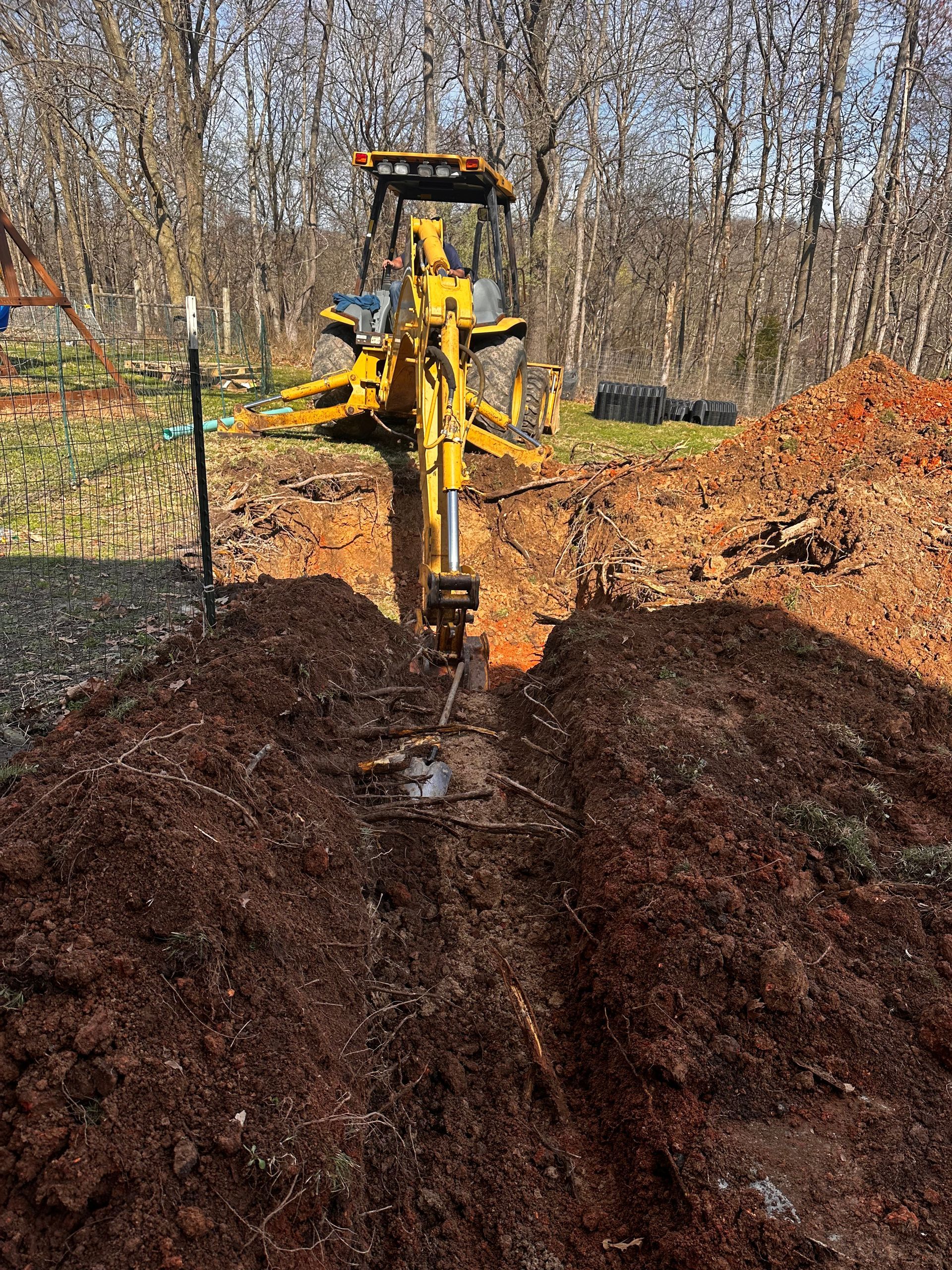 A yellow tractor is digging a hole in the dirt
