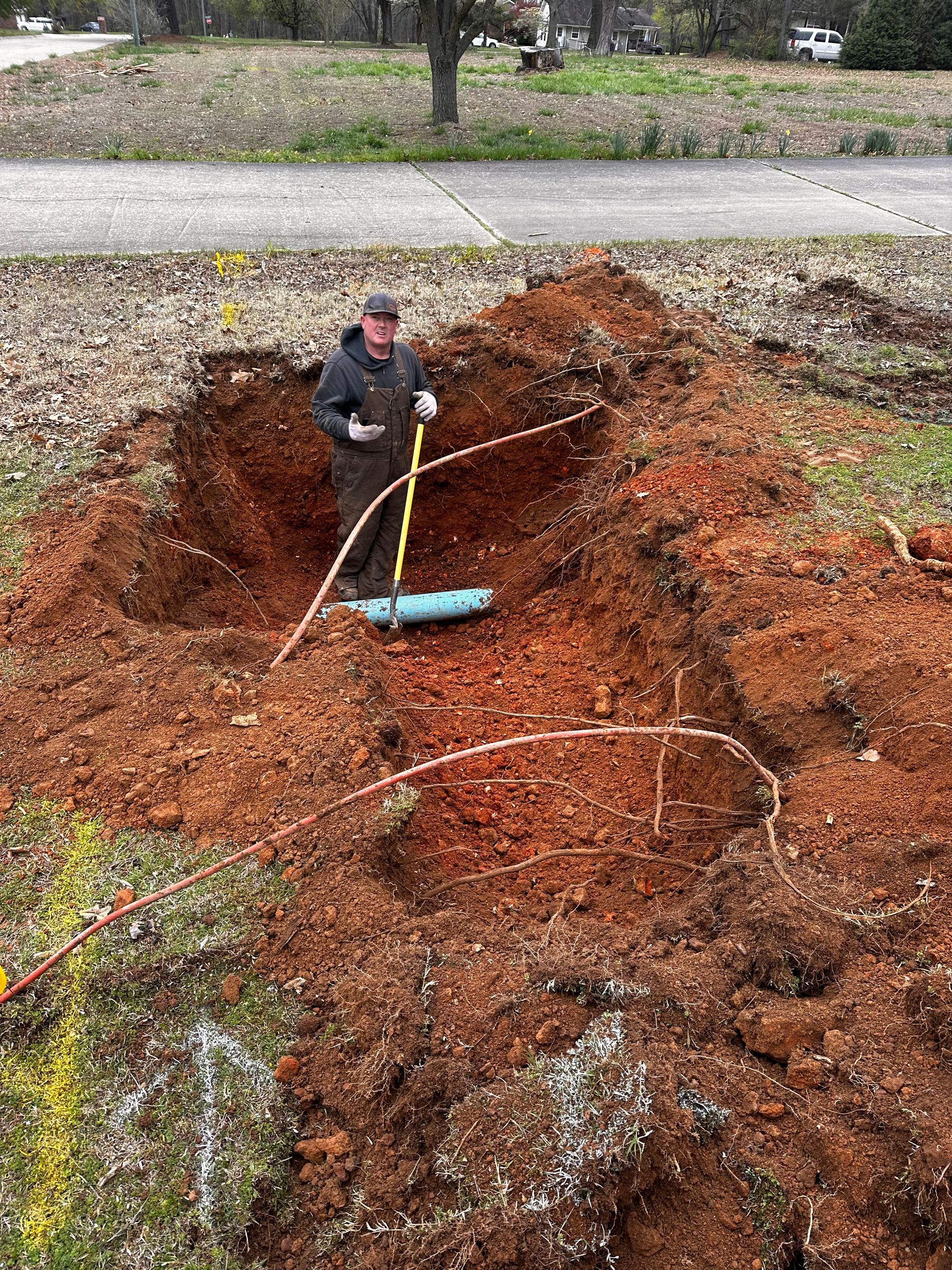 A man is digging a hole in the dirt with a shovel.