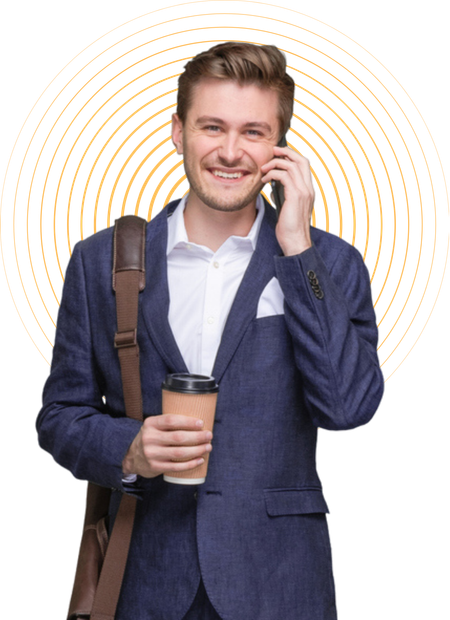 A man in a suit is talking on a cell phone while holding a cup of coffee.