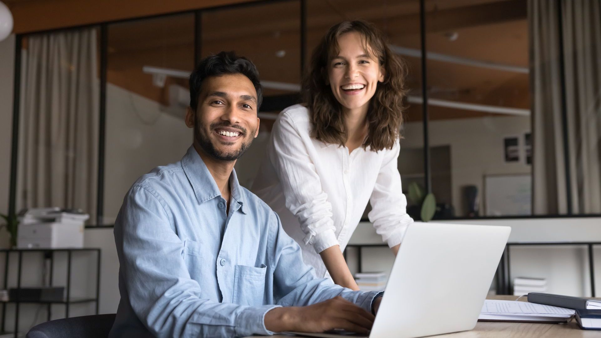 Peoplebank employees smiling at a laptop in a modern office
