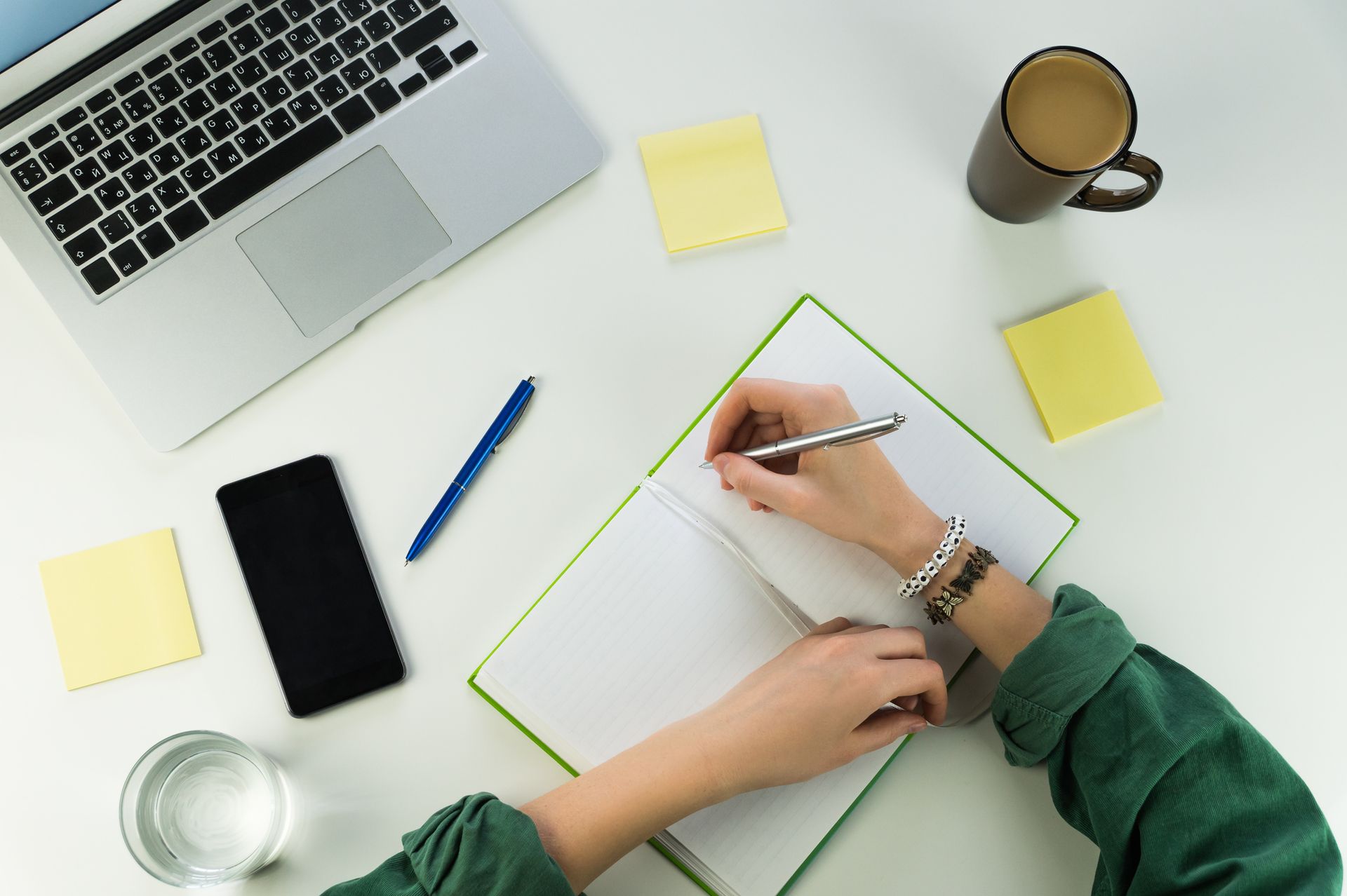 A person is sitting at a desk writing in a notebook.