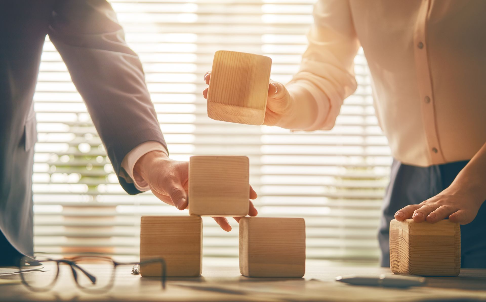 A man and a woman are stacking wooden blocks on top of each other.