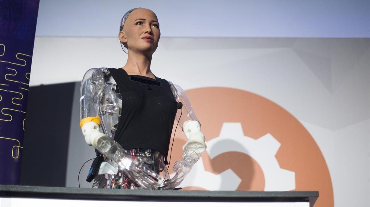 A robot is standing at a podium with a gear in the background.