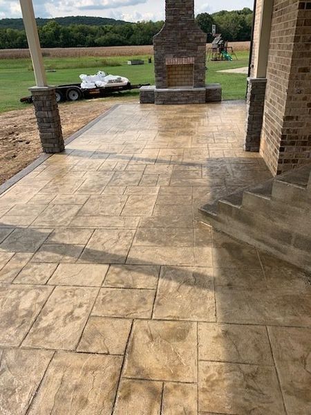 Stone patio with brick fireplace, steps, and outdoor view of a grassy yard with a parked golf cart.