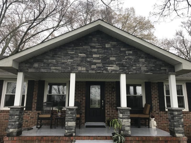 Small house with stone porch and white columns under leafless trees