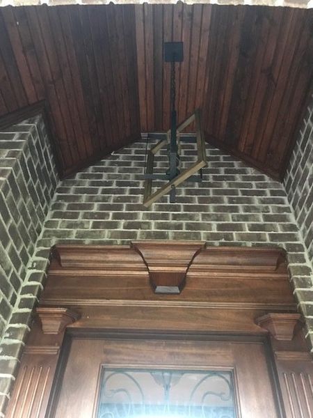 Brick archway with dark wood trim and a hanging light fixture above a doorway