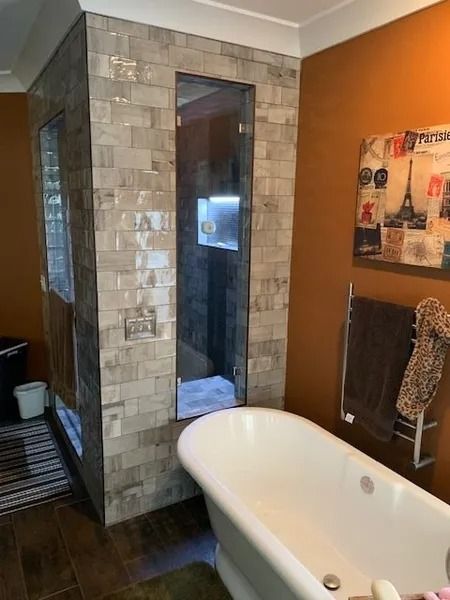 Modern bathroom with freestanding tub, tiled shower column, and orange accent wall