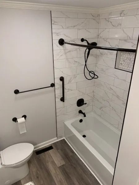 Accessible bathroom with walk-in tub, grab bars, handheld shower, and toilet.