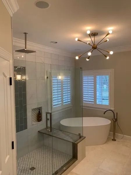 Modern white bathroom with freestanding tub, glass shower, and ceiling light fixture