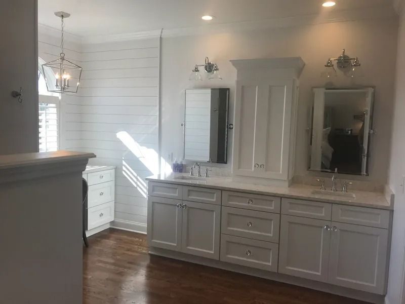 Bright bathroom vanity with gray cabinets, double mirrors, and white shiplap walls in natural light