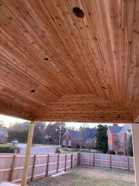 Wood-paneled porch ceiling overlooking a fenced suburban yard and quiet street at dusk