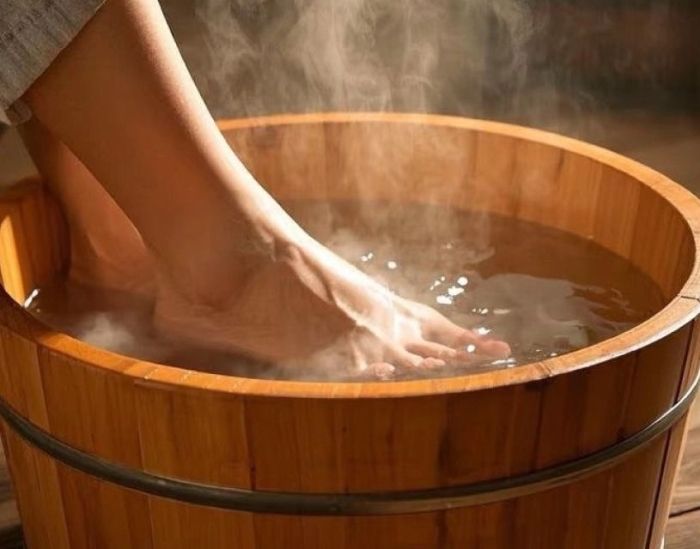Hands giving a back massage; person lying face down, covered in oil, on a massage table.