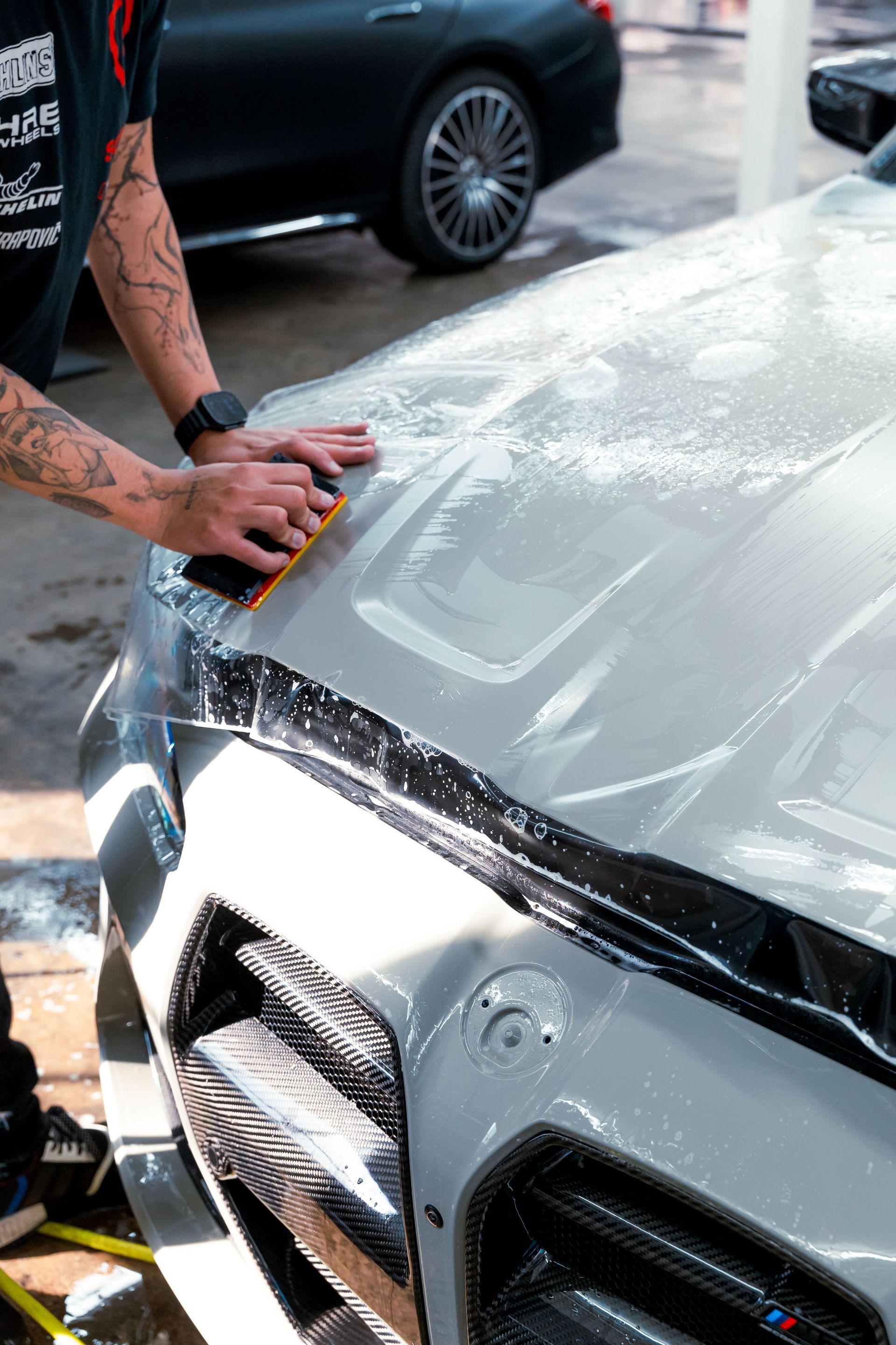 Person washing a silver car hood with a sponge at a car wash