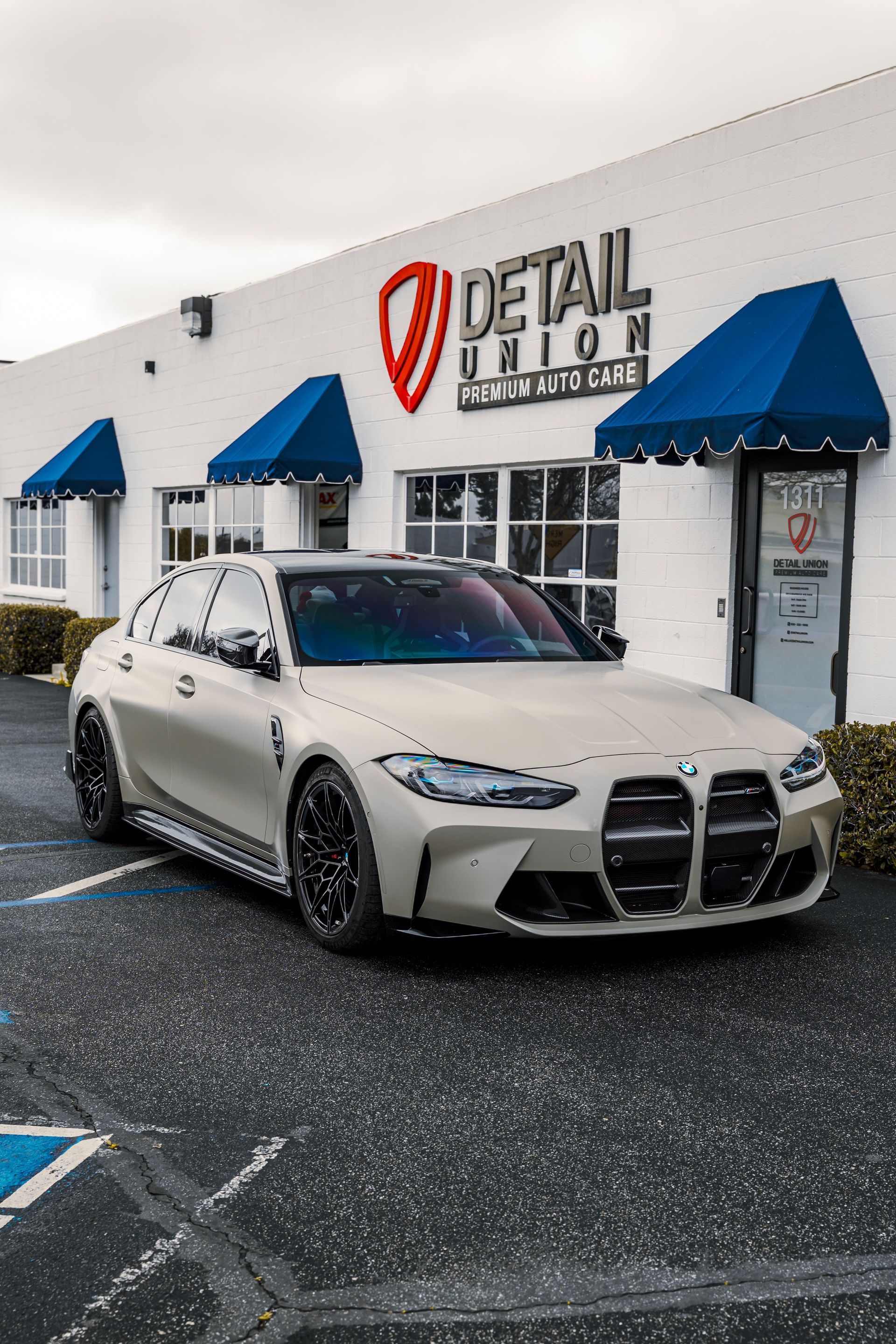 Brown sports car parked outside a Detail Union storefront with awnings
