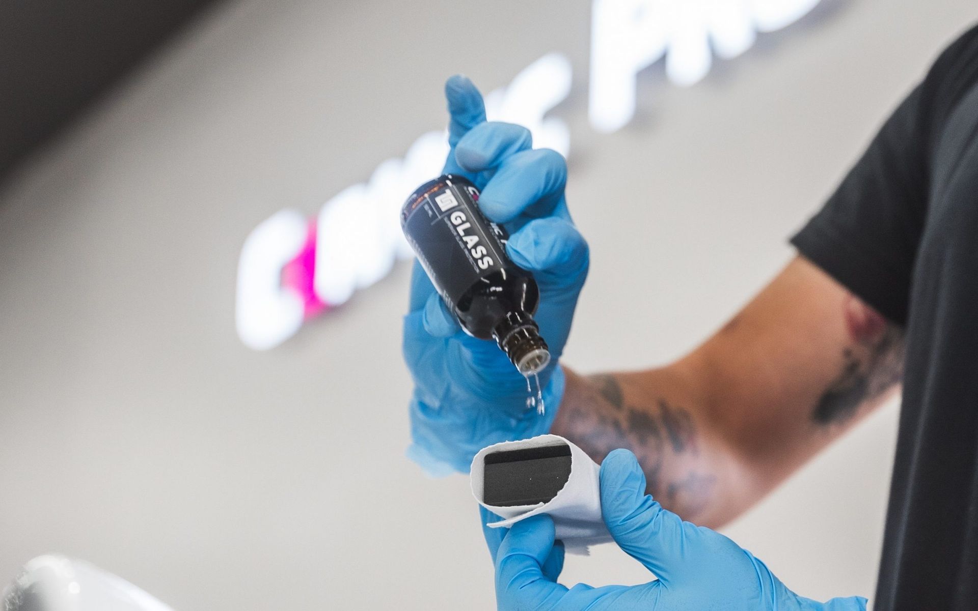 Gloved hand holding a car key fob above a small handheld device in a garage setting