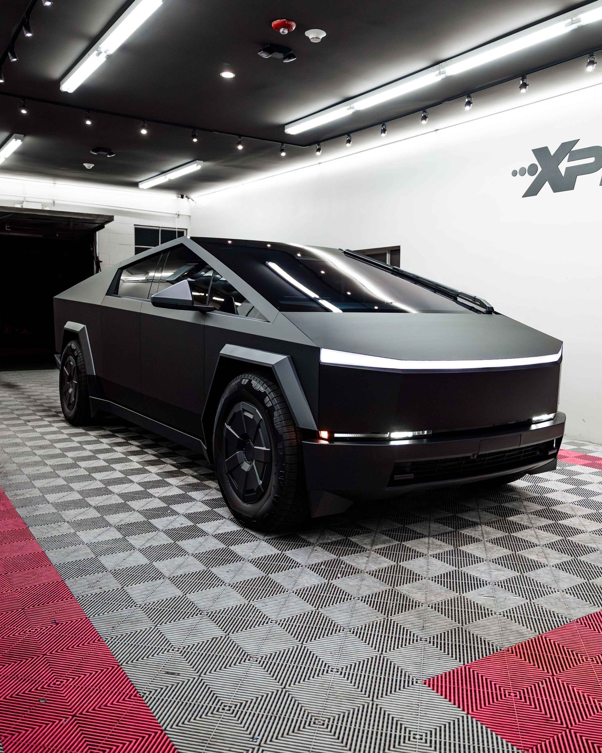 Tesla Cybertruck on display in a showroom, seen front-left with a silver body and black wheels.