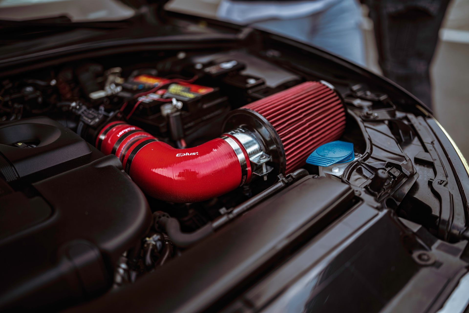 Close-up of a car engine bay with a red air intake hose and filter