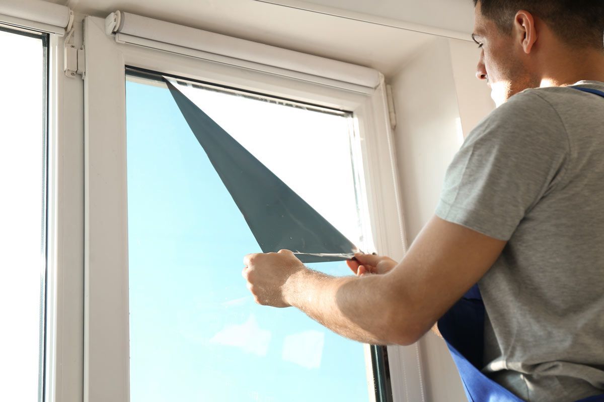 Person applying window film to a bright window with a squeegee