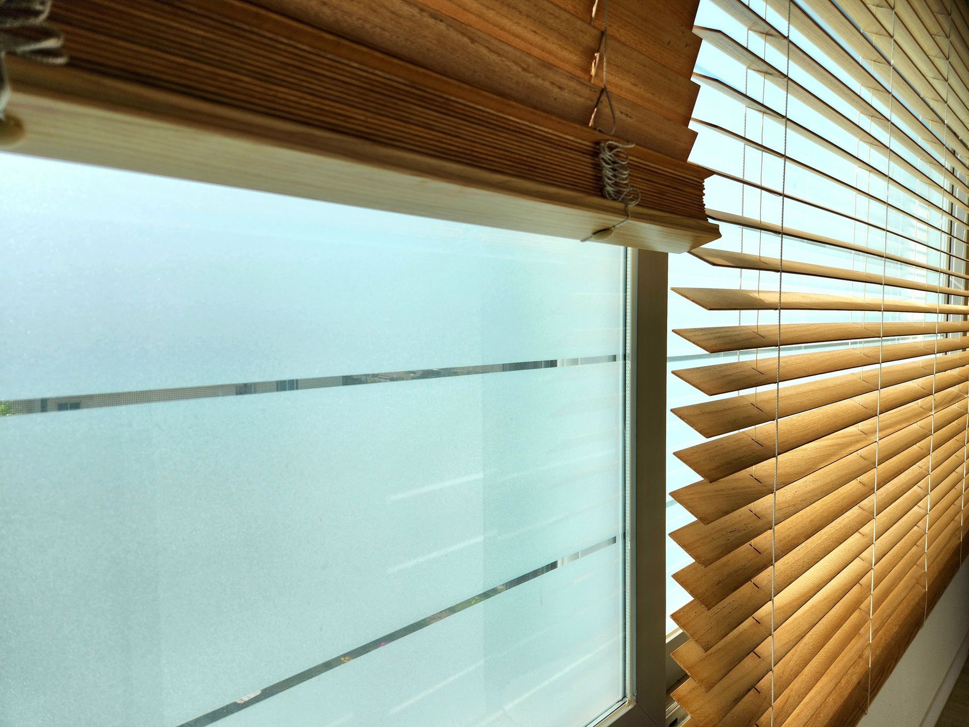 Sunlit window with frosted glass and partially closed wooden blinds