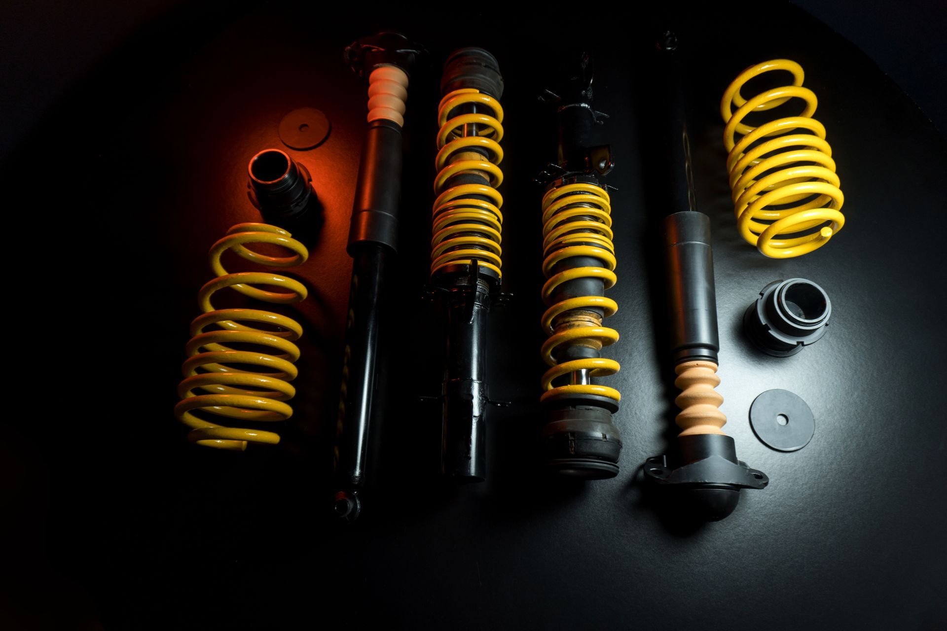 Assorted black and yellow car suspension shocks and coil springs on a dark background