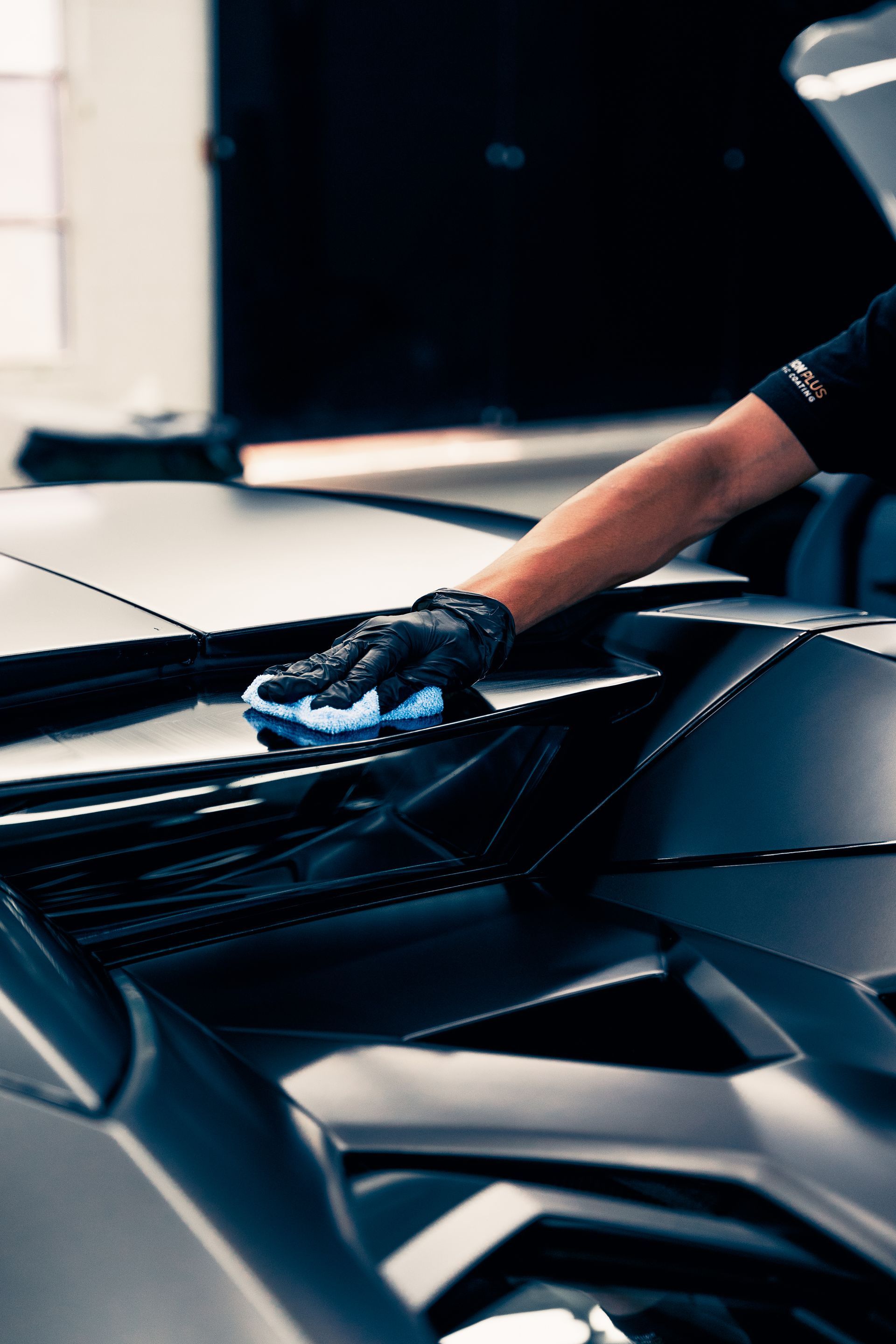 Hands applying clear protective film to a red car headlight.