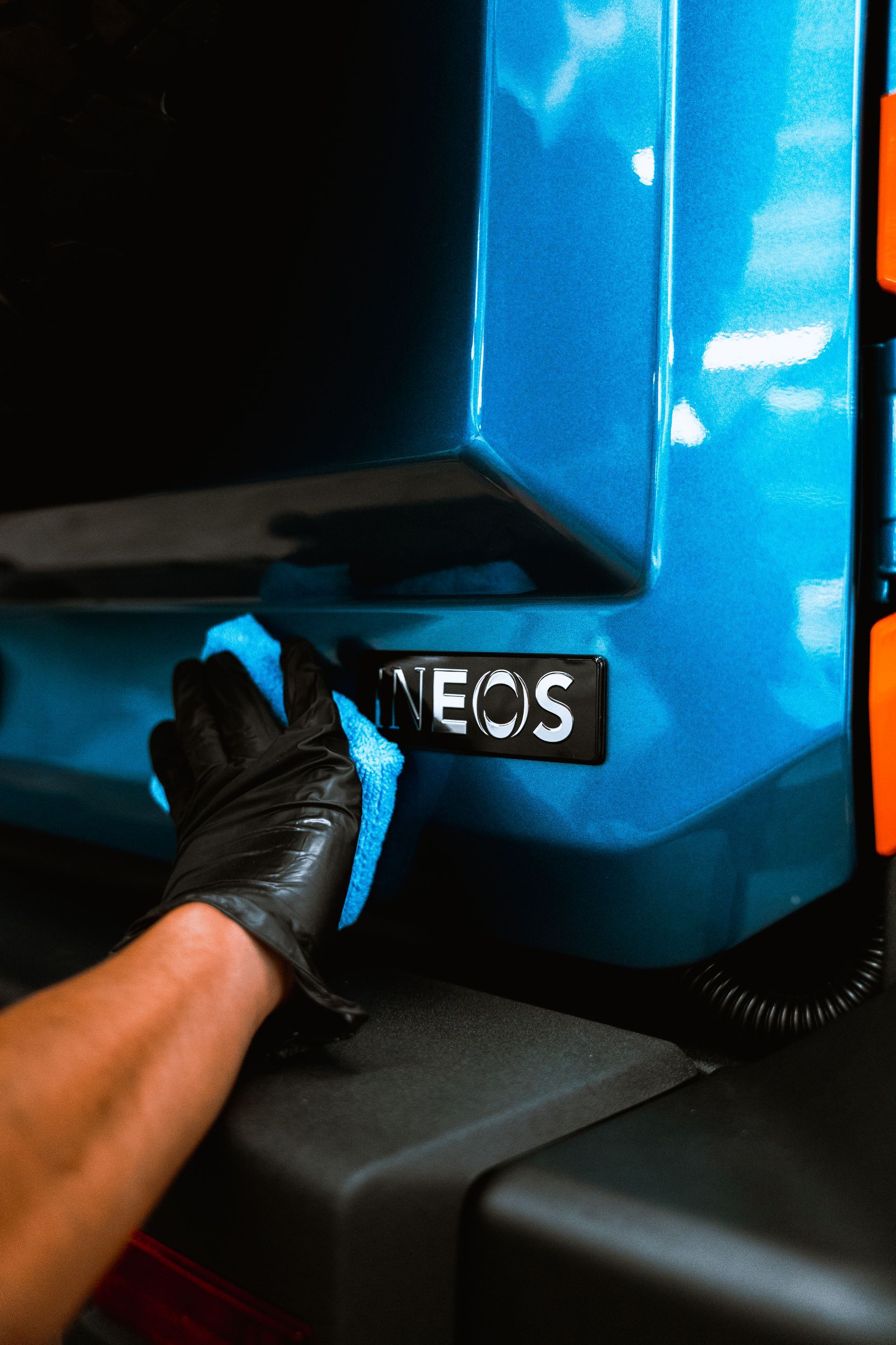 Gloved hand polishing the blue side panel of a vehicle near an “ECOS” badge