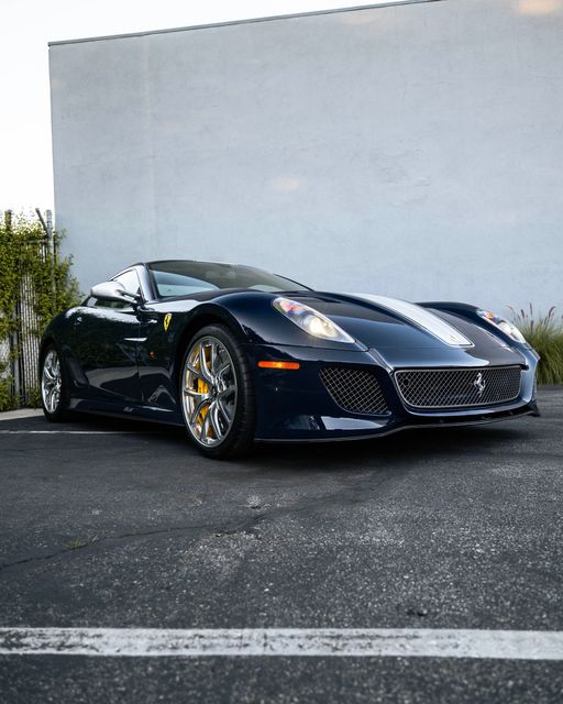 Black sports car parked on asphalt in front of a plain white wall