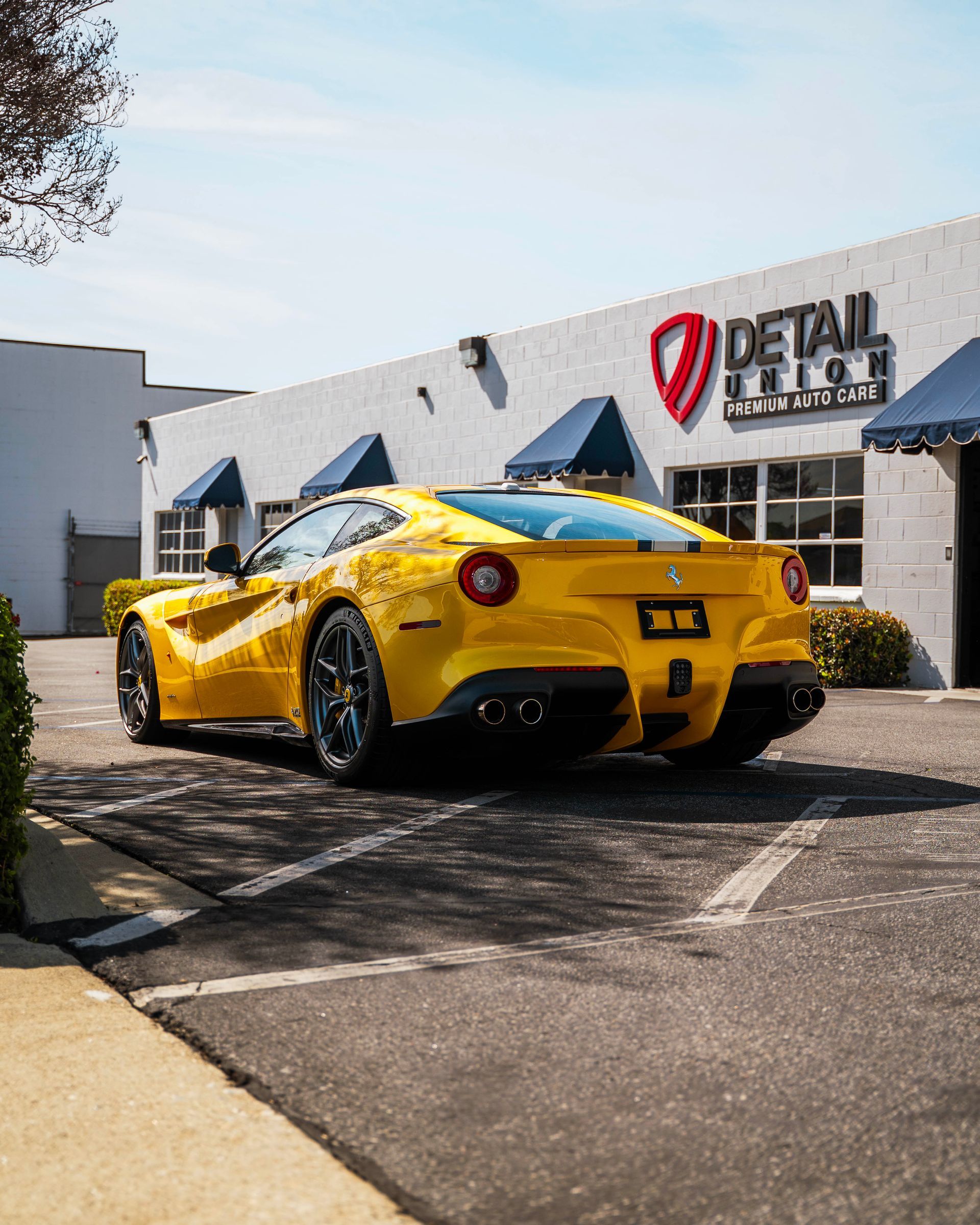 Yellow sports car parked outside a detailing shop on a sunny day
