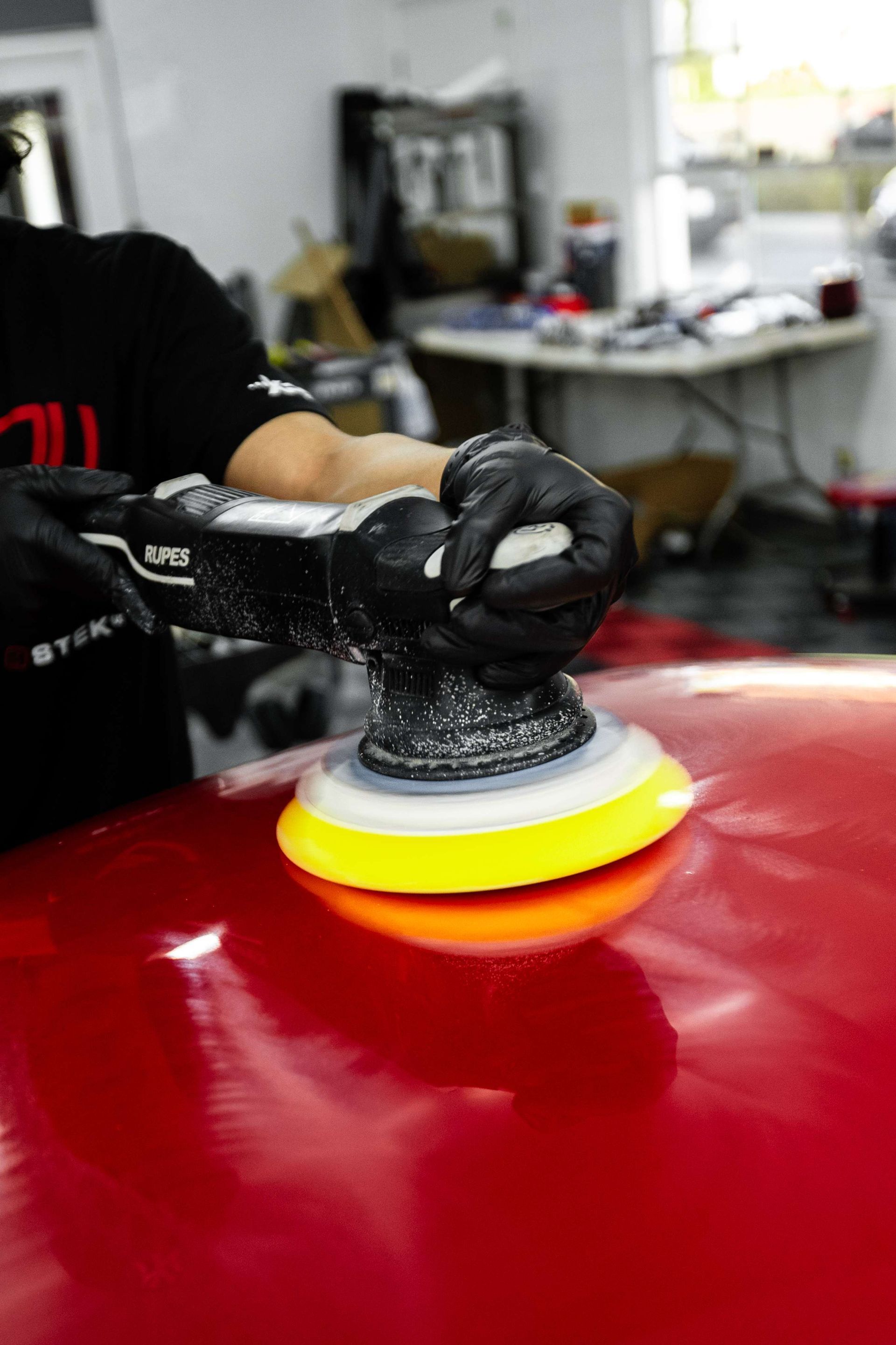 Hands applying clear protective film to a red car headlight.