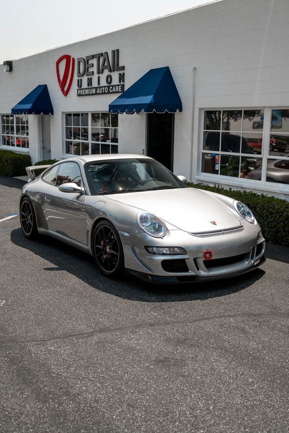 Brown Porsche parked outside a Detail Union shop with black awnings