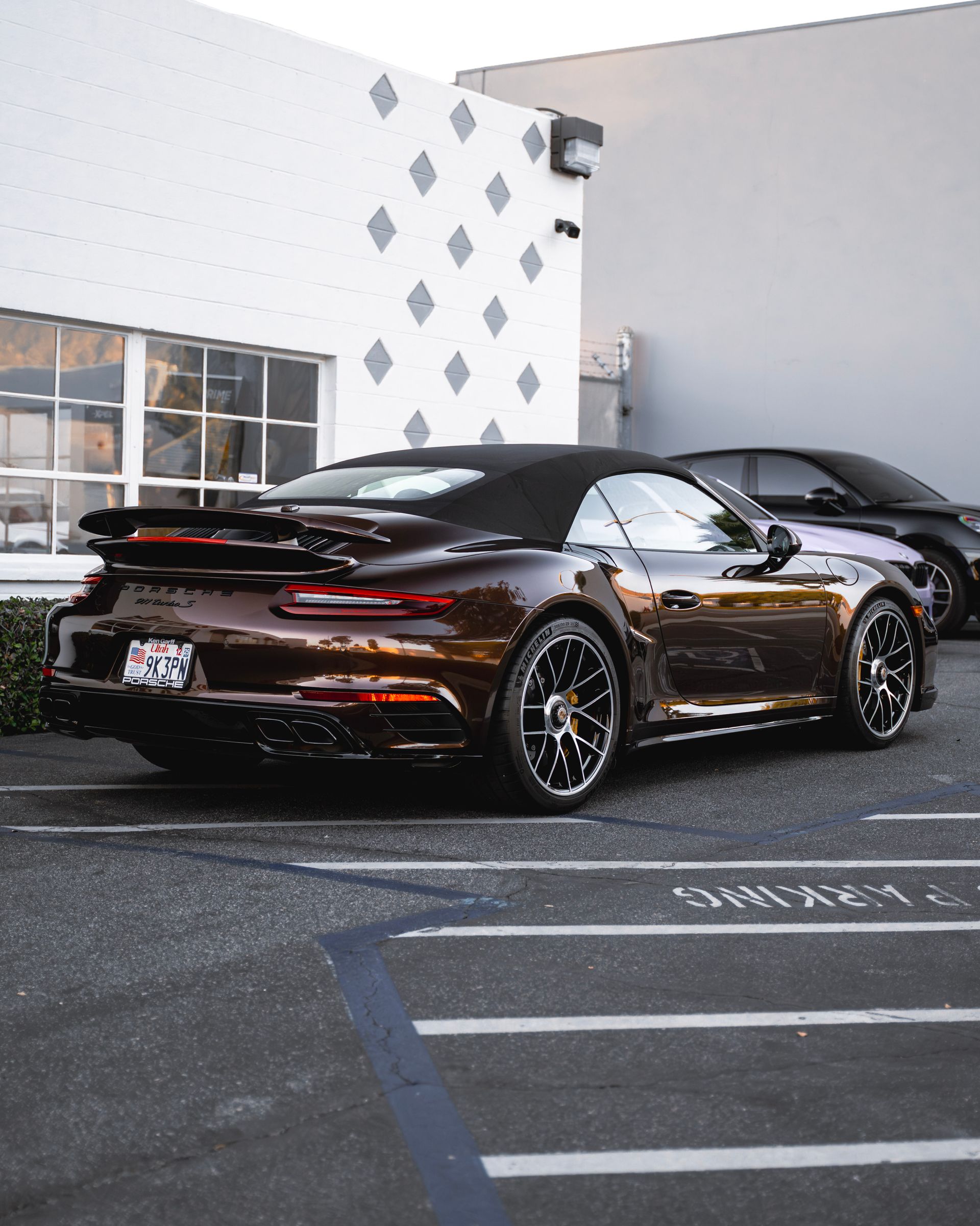 Black sports car parked outside a building with diamond-pattern wall accents.
