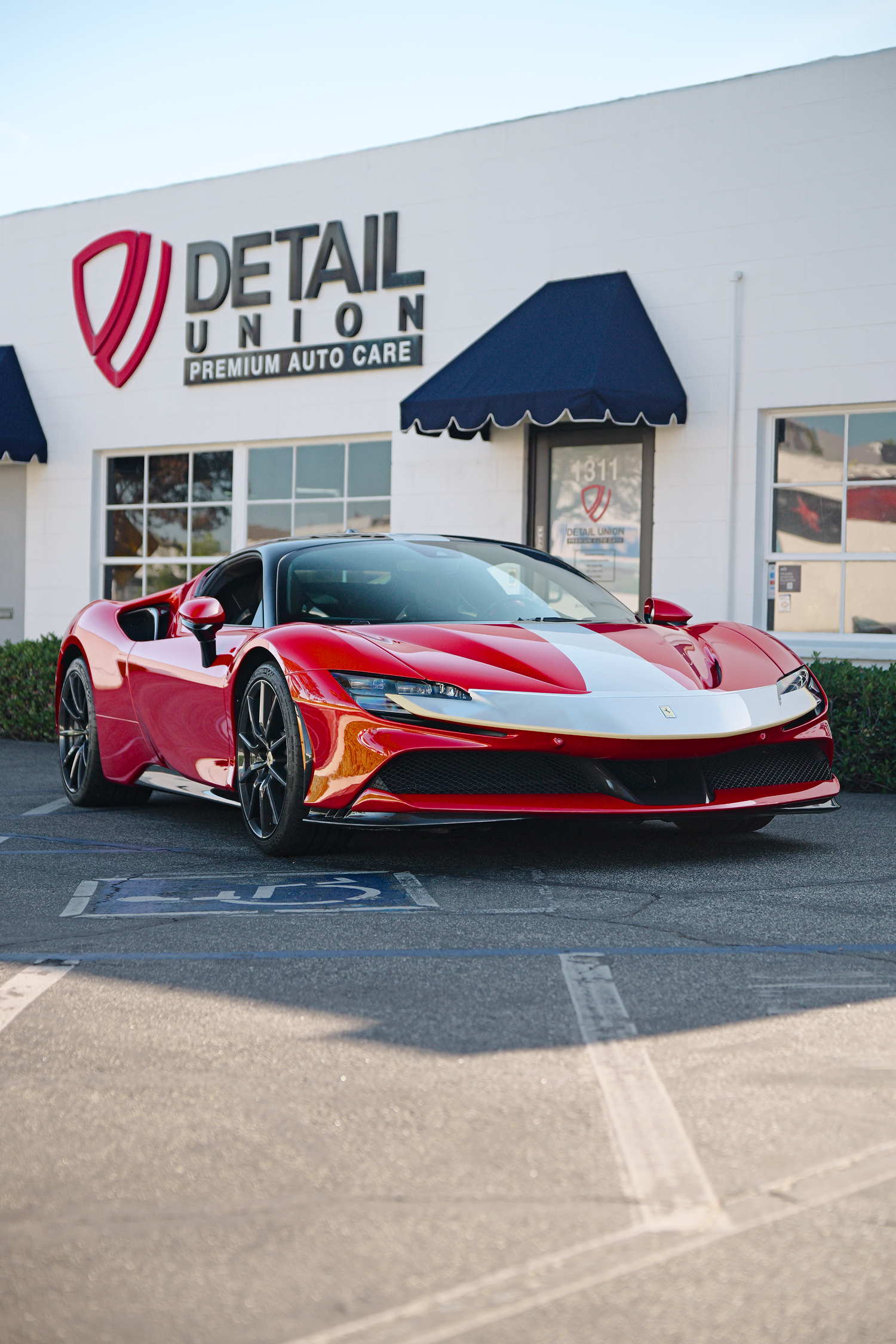 Orange sports car parked outside a detail shop with a black-and-white building facade
